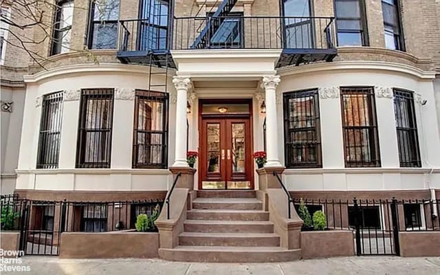 view of exterior entry featuring french doors and a balcony