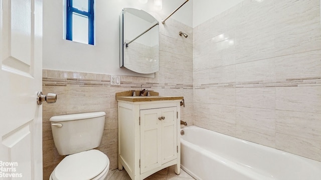 full bathroom with vanity, washtub / shower combination, toilet, and tile walls