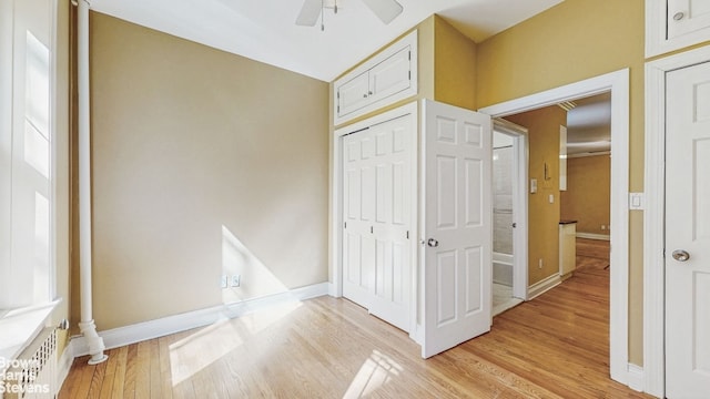 unfurnished bedroom featuring a closet, baseboards, ceiling fan, and light wood-style floors