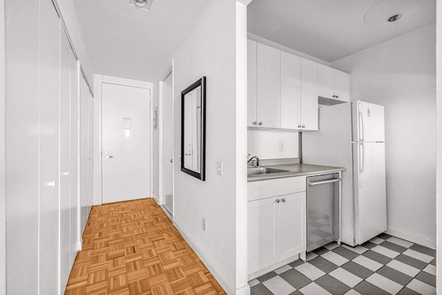 kitchen with white cabinets, dishwasher, light countertops, light floors, and a sink