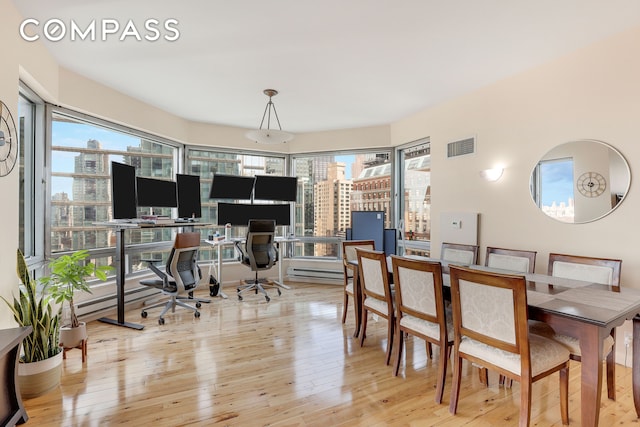 dining area featuring visible vents, a baseboard heating unit, and hardwood / wood-style floors