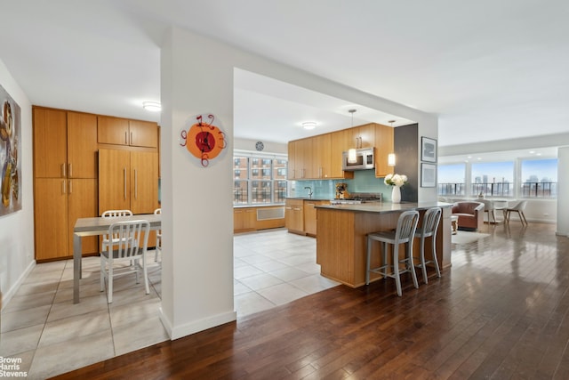 kitchen featuring a peninsula, stainless steel microwave, backsplash, and a wealth of natural light