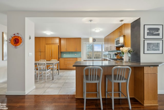 kitchen featuring dark countertops, decorative backsplash, white microwave, a peninsula, and built in refrigerator