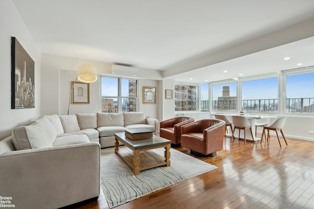 living room with plenty of natural light, a view of city, a wall unit AC, and hardwood / wood-style flooring