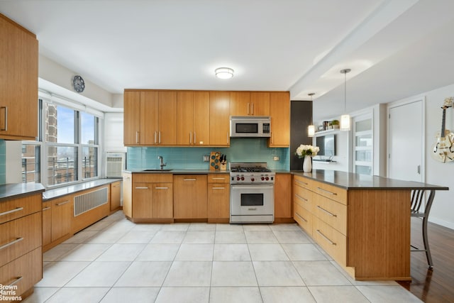 kitchen with decorative backsplash, white microwave, a peninsula, high end stainless steel range oven, and a sink