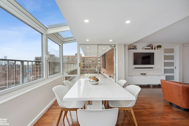 dining space with baseboards, recessed lighting, wood finished floors, and a skylight