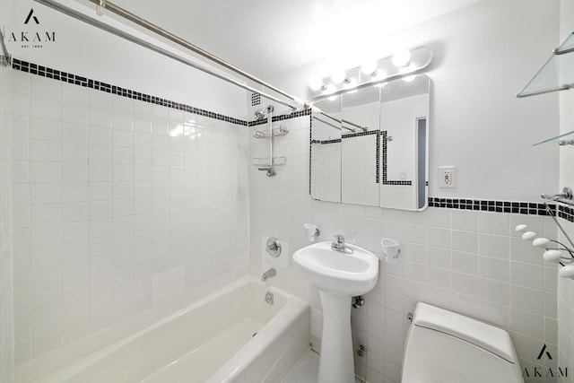 bathroom featuring a sink, shower / tub combination, tile walls, and toilet