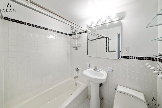 211 Thompson St Unit 4-C, New York City, NY 10012 - bathroom featuring toilet, bathing tub / shower combination, tile walls, and a sink