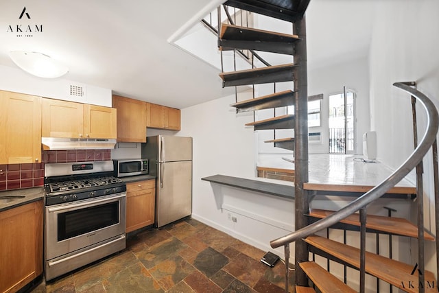 kitchen featuring visible vents, dark countertops, appliances with stainless steel finishes, stone finish flooring, and under cabinet range hood