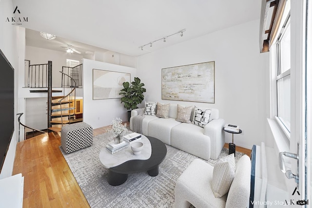 living area featuring stairs, a ceiling fan, track lighting, and wood finished floors