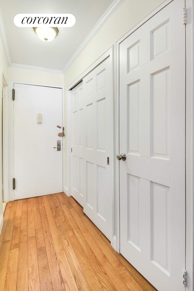 entryway with light wood-style flooring and ornamental molding