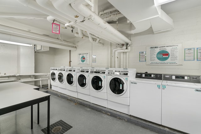 common laundry area featuring concrete block wall and washer and clothes dryer