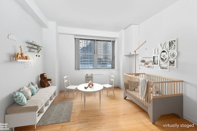 bedroom with a nursery area and light wood-type flooring