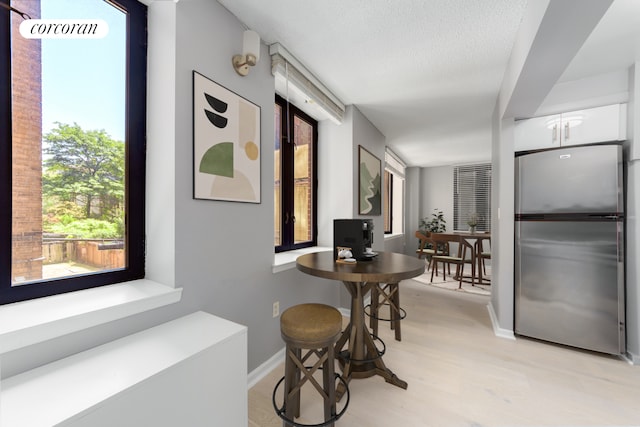 hall featuring light wood-style floors, baseboards, and a textured ceiling