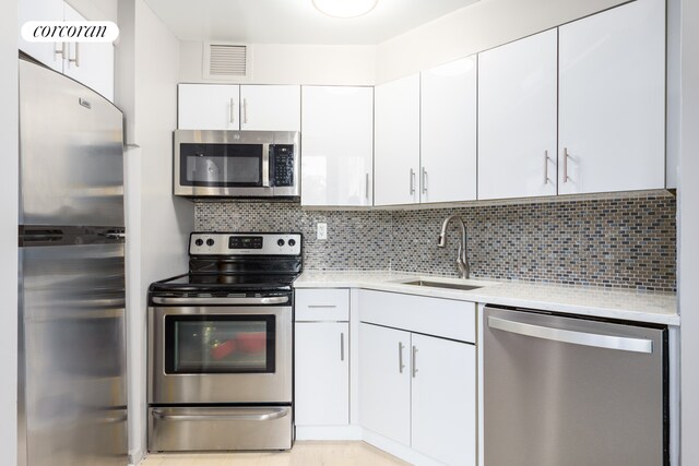 kitchen with visible vents, a sink, tasteful backsplash, stainless steel appliances, and light countertops