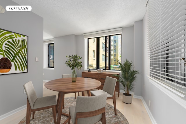 dining area featuring light wood-type flooring, baseboards, a textured ceiling, and visible vents