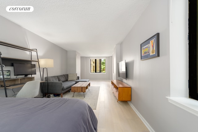 bedroom featuring baseboards, visible vents, a textured ceiling, and light wood-style floors