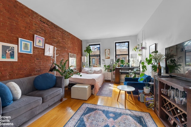 bedroom with brick wall and wood finished floors