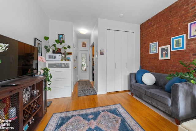 living room with brick wall and light wood-style flooring