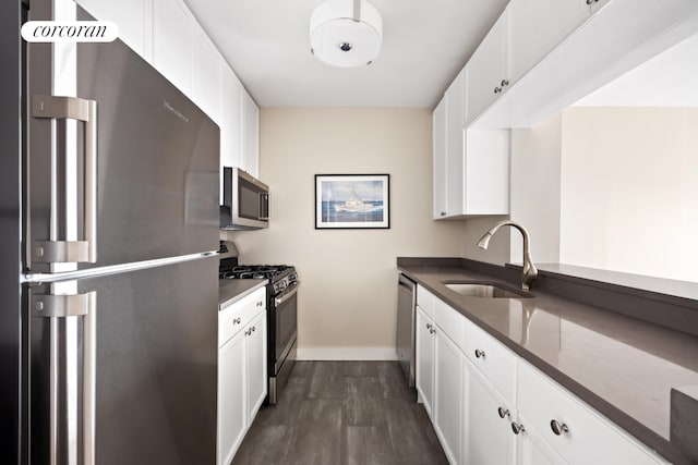 kitchen with white cabinets, dark wood-style flooring, stainless steel appliances, and a sink