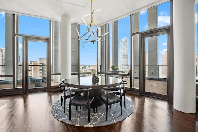 dining area featuring dark wood-style floors, a view of city, a wall of windows, and a notable chandelier