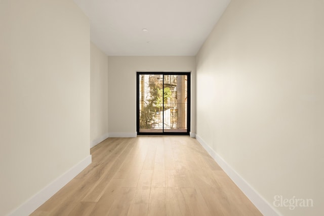 spare room with baseboards and light wood finished floors