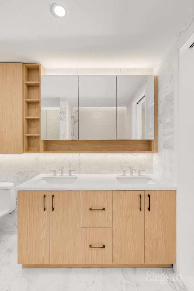 bathroom with double vanity, toilet, marble finish floor, and a sink