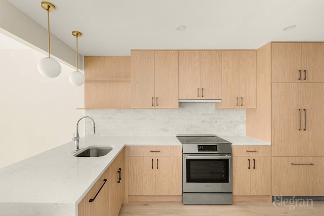 kitchen with stainless steel electric stove, light brown cabinets, and a sink