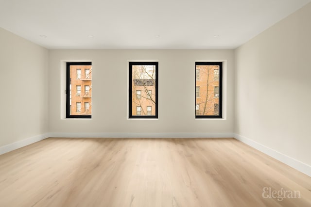 empty room featuring baseboards and light wood finished floors