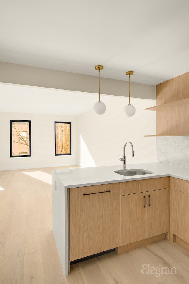 kitchen featuring a sink, light wood-style floors, light brown cabinetry, and light countertops