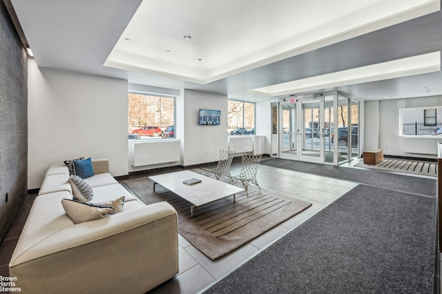 living room with a raised ceiling, a healthy amount of sunlight, and tile patterned floors