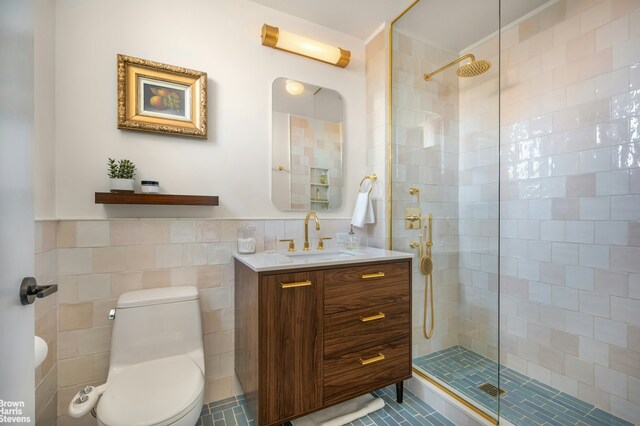 bathroom featuring tile walls, toilet, wainscoting, a shower stall, and vanity