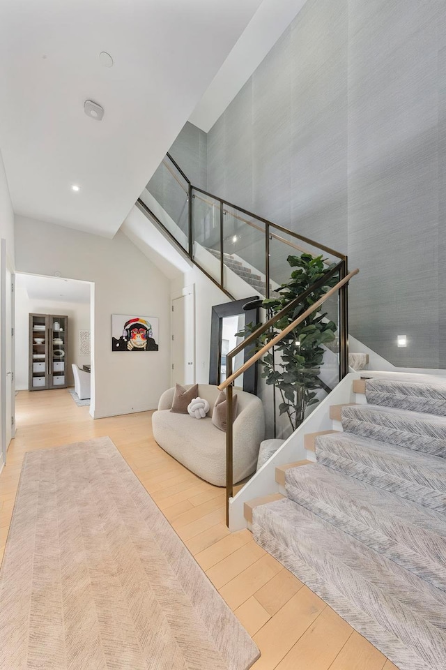 stairs featuring a towering ceiling and wood finished floors