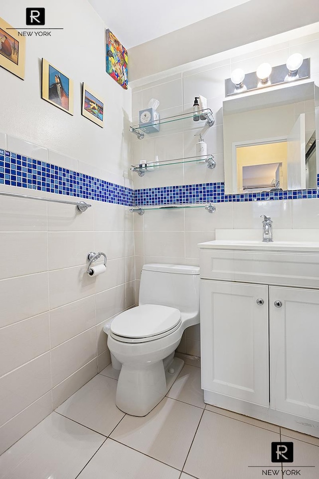 bathroom featuring tile patterned floors, tile walls, toilet, and vanity