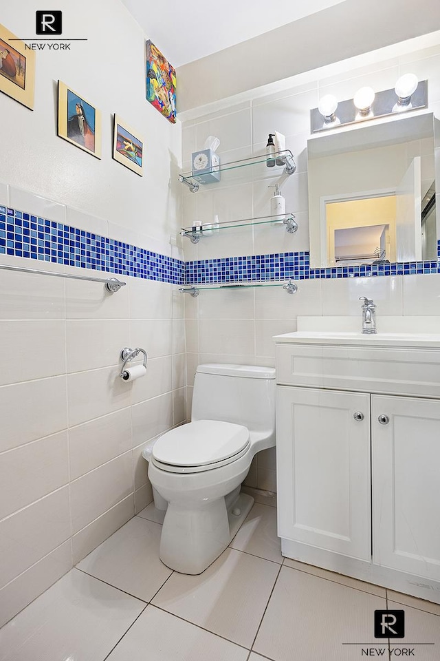 bathroom featuring toilet, tile walls, tile patterned flooring, and vanity