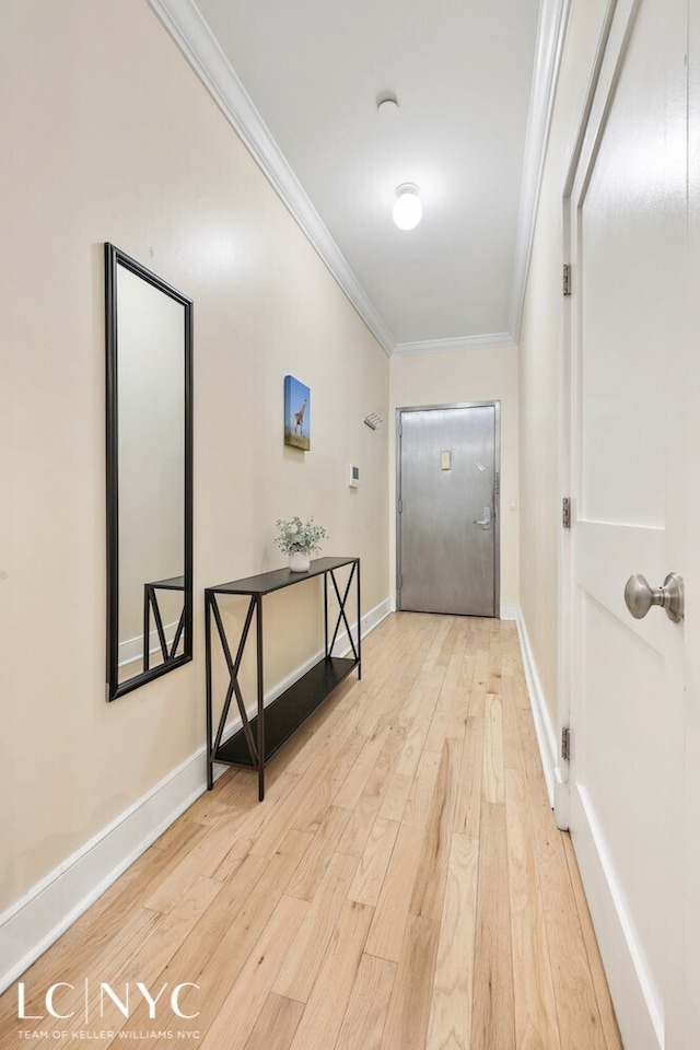 hall with baseboards, light wood-style floors, and crown molding