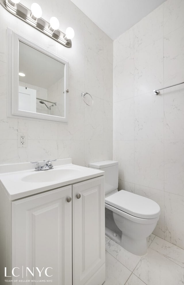 bathroom featuring marble finish floor, tile walls, vanity, and toilet