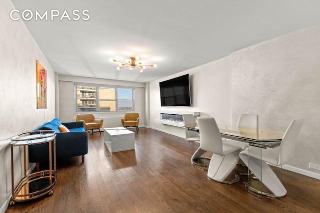 living room featuring dark wood finished floors, baseboards, and an inviting chandelier