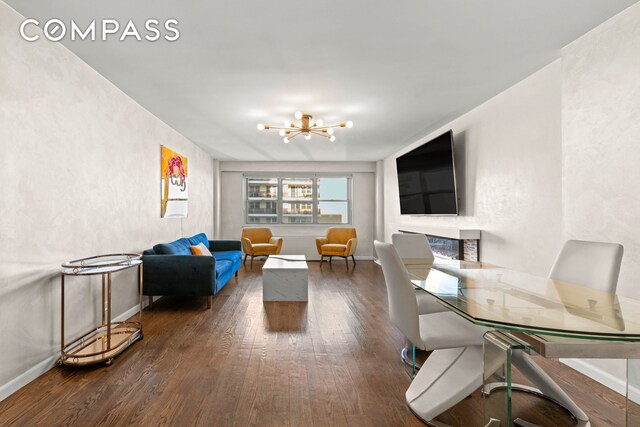 living area with a chandelier, hardwood / wood-style flooring, and baseboards