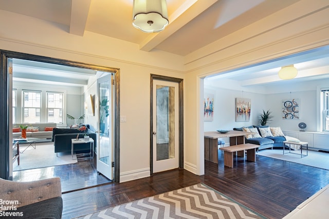 doorway featuring baseboards, beamed ceiling, and wood finished floors