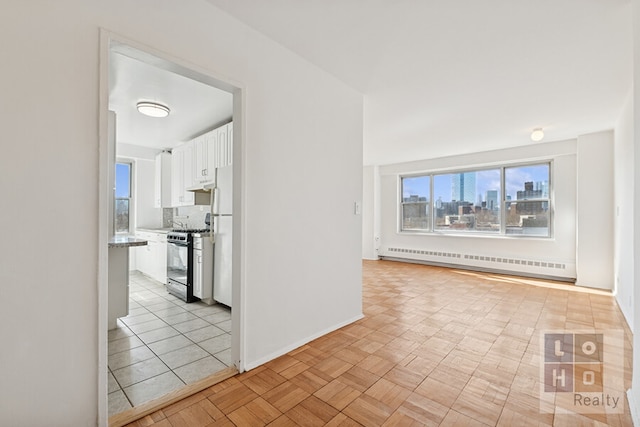 corridor with a baseboard heating unit, a view of city, and baseboards