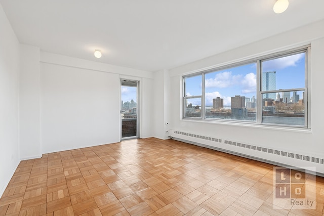 spare room featuring a view of city, baseboards, and baseboard heating