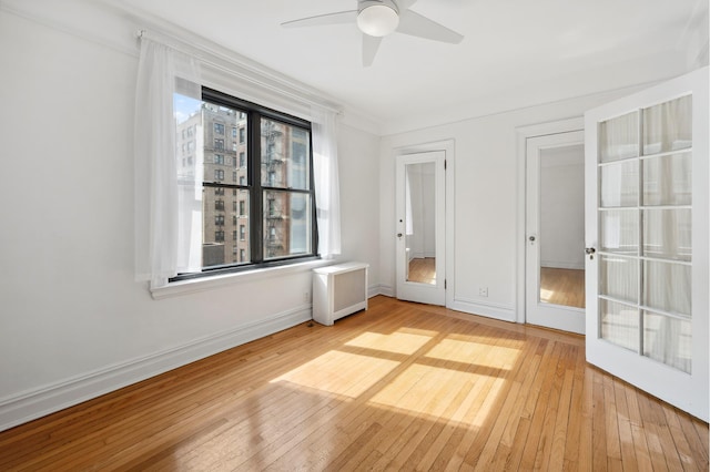 unfurnished bedroom with baseboards, light wood-type flooring, a ceiling fan, and radiator