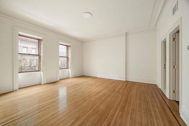 unfurnished room featuring light wood-style floors, baseboards, visible vents, and ornamental molding