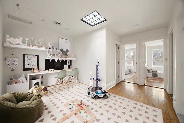 recreation room with visible vents, baseboards, and wood finished floors