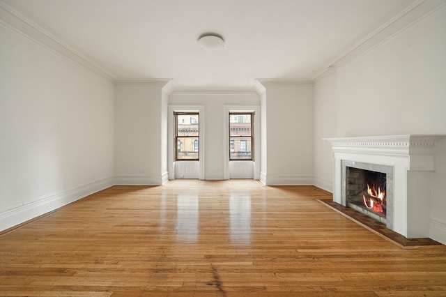 unfurnished living room with crown molding, a fireplace with flush hearth, light wood finished floors, and baseboards