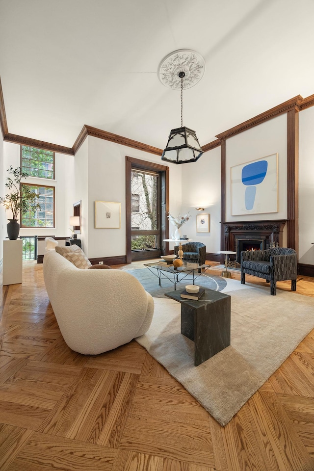 living area featuring baseboards, plenty of natural light, ornamental molding, and a lit fireplace