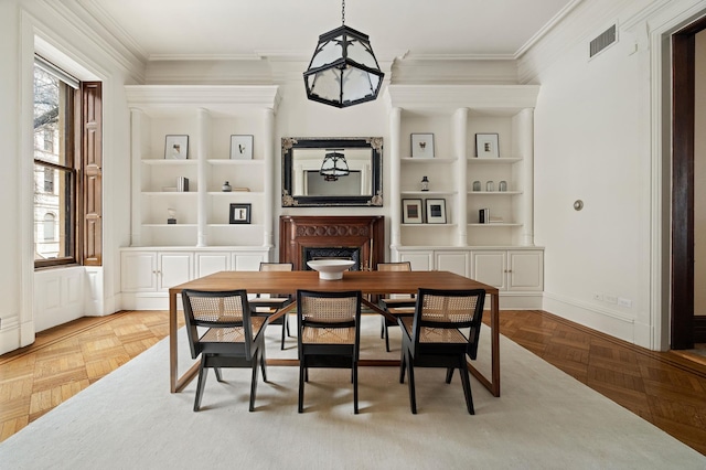 dining room featuring a fireplace, visible vents, built in features, and ornamental molding