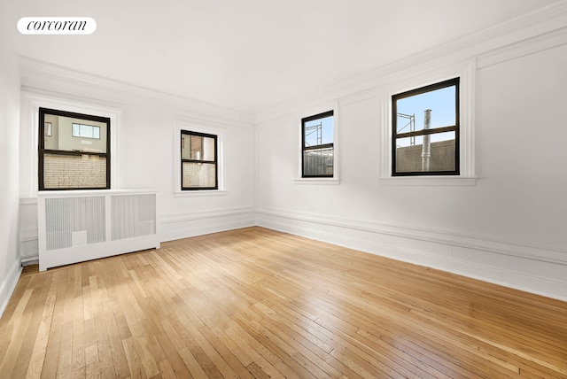 unfurnished room with crown molding, light wood finished floors, visible vents, and radiator