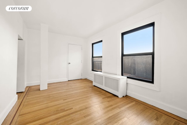 unfurnished room with baseboards, radiator heating unit, visible vents, and light wood-style floors